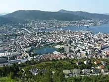 Blick von einer Anhöhe herab auf eine Großstadt, rechts im Bild ist das Meer zu sehen