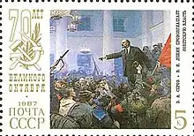 Briefmarke mit einem abgebildeten Ölgemälde, auf dem ein Mann in einer Menschenmenge mit roten Fahnen und Gewehren spricht. An beiden Seitenrändern der Briefmarke stehen kyrillische Wörter und die Jahreszahl 1987. Als Logo sind auf einem Lorbeerzweig die sich kreuzenden Sichel und Hammer gezeichnet.