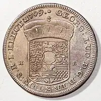 1 Thaler, Georg Ludwig 1709 als Kurfürst von Braunschweig-Lüneburg und Erzbannerträger, in Erwartung des Amts als Erzschatzmeister (Welter 2138)Vs.: Wappen von Braunschweig-Lüneburg mit Kurhut und Warteschild