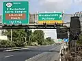 Grüne Wegweiser an Schilderbrücke über Schnellstraße mit 3 Fahrspuren und 1 Abbiegespur. Links Logo 120 North und E Rutherford / Sports Complex / Exit 1 Mile. Braun hinterlegt: American / Dream. Rechts Richtungspfeil und Meadowlands / Parkway. Gelb hinterlegt: Exit Only.
