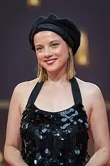 Jella Haase im schwarzen Trägerkleid vor Sponsorenwand