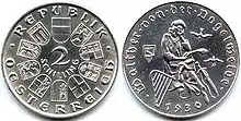 Zwei silberfarbene Münzen nebeneinander, die linke trägt die Ziffer 2, von Wappen umrundet, die rechte zeigt die Figur eines Mannes in einem Gewand, dabei eine Harfe