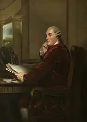 Gemälde des Duke of Portland, der dem Stil der Zeit entsprechend eine gepuderte weiße Perücke sowie einen weinroten Samtanzug und weiße Strümpfe trägt. Er sitzt auf einem geschnitzten, verzierten Stuhl, sein Blick geht nach links, er sieht nachdenklich aus. Vor ihm ein Schreibtisch, auf dem sein linker Arm ruht, in der Hand hat er einige Unterlagen, auf dem Schreibtisch sind ebenfalls zahlreiche Unterlagen verteilt. Dahinter sind auf dem Schreibtisch verteilt auch einige Bücher sowie eine Skulptur. Seine rechte Hand stützt sein Kinn.