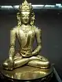 Eine goldfarbene Figur sitzt im Schneidersitz.