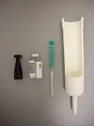 Von links nach rechts: Prüfstrahler, Glasflasche für Radionuklid in wässriger Lösung, Spritze und Proben-Einsatz.