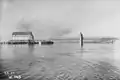 Fertiges Weserwehr, vom Oberwasser gesehen. Die Fußgängerbrücke führt über den Weserpfeiler zum Flusspfeiler, links das fertige Turbinenhaus