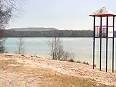 Altwarmbüchener See mit Badestrand, dahinter der Nordberg der Deponie Hannover-Lahe
