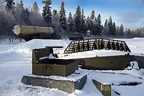 Im Vordergrund des Bildes zu erkennen ist das verschlossene Startsilo, im Hintergrund ein 5T92-Transportfahrzeug auf Basis eines MAZ-543M mit dem zylindrischen Behälter, in dem eine 53T6-Rakete transportiert wird.