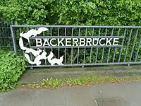 Das Namensschild der Brücke mit den vier Eichhörnchen wurde 1971 von dem Metall- und Steinbildhauer Ernst Hanssen erstellt.