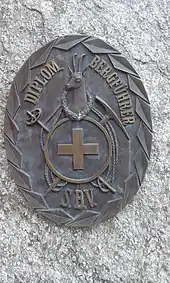 Das Originalabzeichen in Bronze (70 × 55 cm) der diplomierten Bergführer des Schweizer Bergführerverbands (S.B.V.) auf dem Bergführerdenkmal  in St. Niklaus Dorf
