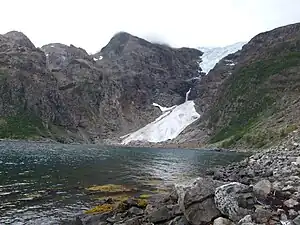 Oben der Isfjordjøkelen, ein Teilgletscher des  Øksfjordjøkelen, unten der Gletscher Nerisen, ein  sogenannter „regenerierter Gletscher“, der von den Lawinen des Isfjordjøkelen gespeist wird. Das Eis der Gletscher wurde bis 1949 von den Fischern und Händlern zu Kühlung des Fangs genutzt.