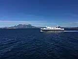Foto einer fahrenden Fähre auf dem Meer, im Hintergrund Berge