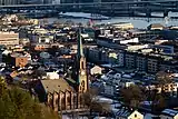 Foto einer an einem Fluss gelegenen Stadt, mit einer Kirche im Vordergrund.