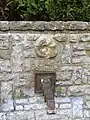 Brunnen an der Weggabelung Bischof-Weiß-Straße und Sperrweg, der zum Sperrberg führt, Detail Quellhahn und darüber eingemauerter Ammonit