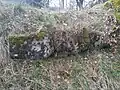 Reihe behauener und bemooster Sandsteine in Nahsicht.