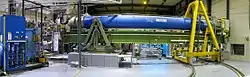 Das CAST-Experiment am europäischen Kernforschungszentrum CERN. Dargestellt ist der supraleitende CAST-LHC-Magnet mit Nachführsystem und das Helium-Kühlsystem zum Betrieb des Magneten (links).