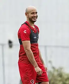 Bild von Carlos Gonzales. Rotes Trikot und Glatze.