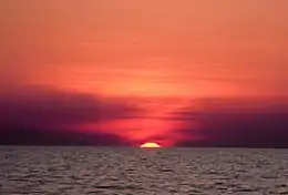 Oben roter Himmel, unten der Ozean mit kleinen Wellen wird vom Himmel erleuchtet.