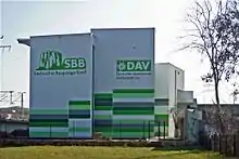 Blick auf die Kletterhalle mit zwei Türmen, auf einem mit Logo des Sächsischen Bergsteigerbundes, auf dem anderen das Logo des Deutschen Alpenvereins
