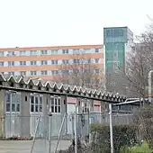 mehrere graue alte Garagenzufahrten hinter einem hohen siebenstöckigem Gebäude