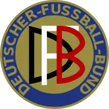 Abgebildet ist das Logo des Deutschen Fußball-Bundes von 1900 – 1945. Es stellt einen Freis dar, der in blau und gold gehalten ist. Am äußeren Rand wird der Schriftzug DEUTSCHER-FUSSBALL-BUND im Kreis geführt. In der Mitte befindet sich die Abkürzung "DFB": Jeder Buchstabe in einer anderen Farbe, weiß schwarz und rot.
