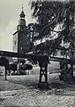 Das Treffurter Rathaus in den 1920er Jahren (vor 1925) mit schieferverkleidetem Turm und der hölzernen Wasserleitung im Vordergrund, die aus der Quelle des Normannsteins 15 öffentliche Brunnen in Treffurt versorgte.