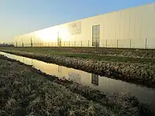 Lagerhalle der Kunststoff-Firma RPC Bramlage (heute Berry Bramlage genannt) westlich der Fischteiche des Fischereivereins Dinklage (vor der Renaturierung des Baches).