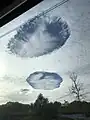 Drei Hole-Punch Clouds fotografiert aus dem TGV Basel-Paris in der Nähe von Saint-Florentin, Frankreich