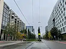 Foto einer von größeren Gebäudekomplexen gesäumte Straße, in der Mitte eine Straßenbahnspur