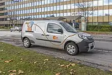 Conni mit einem Stromkabel in der Hand, zu sehen auf einem E-Auto