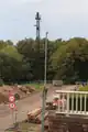 Rohrmast vor dem Rumpenheimer Schloß und südlicher Mast des östlichen Führungsseils. Wie man unschwer erkennen kann, ist die Traverse des Rohr-mastes für eine direkte Leitungsverbindung zum südlichen Mast des östlichen Führungsseils falsch orientiert