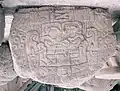 Geometrische Maske mit großen Augen, offenem Mund mit zwei Zahnreihen und heraushängender Zunge (Tlaloc(?))