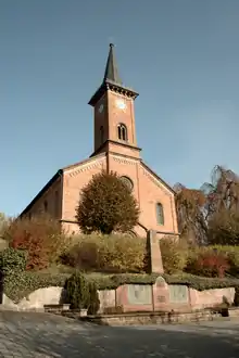 Die ev. Kirche, Frontansicht mit Kriegerdenkmal davor
