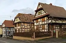 Typische Sundgauer Fachwerkhäuser in Rähmbauweise mit Wetterdächlein am Giebel, Laube mit Andreaskreuzen, das vorderste Haus ohne den im Sundgau üblichen Krüppelwalm
