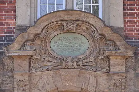 Relief direkt über dem Eingang mit Sinnspruch: Gott zur Ehr, dem Nächsten zur Wehr