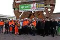 Mitarbeiter, Ehrengäste und Tunnelpatinnen posieren vor dem enthüllten Schneidrad
