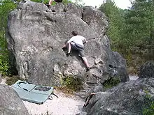 Kind an einem Felsblock, ca. 4 m hoch, mit einer Matte darunter