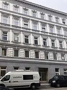 Vier-stöckiges altes Haus, neu renoviert moit davor parkendem Caritas Kleinbus