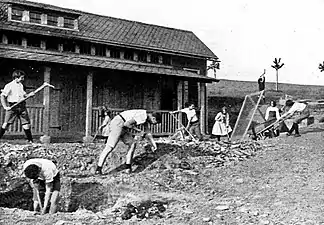 Schülerinnen und Schüler mit Spitzhacke, Schaufel und Durchwurfsieb bei vorbereitenden Arbeiten für Bepflanzungen auf dem Areal des Internats, um 1925