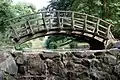 Die Holzbrücke in asiatischem Stil am Auslauf des Fischteiches
