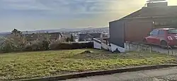 Fundplatz Gönnersdorf im Jahr 2021. Blick vom Mühlenweg nach Süden zur Eduard-Mörike-Straße und zum Rheintal mit der Eifel im Hintergrund. Auf dem Wiesengrundstück neben der schwarz gestrichenen Garage befand sich die Fund­konzentration IV, weiter unten neben der weißen Garage die Fund­konzentration III.