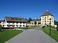 Auffahrt, Blick auf den historischen Schlossturm mit einem Teil der Nebengebäude und dem Jägerhaus mit Schloss Ladl.