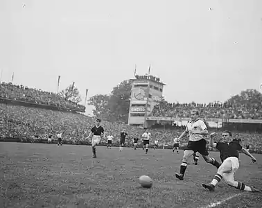 86. Minute: Mit letzter Kraft wirft sich Puskás in die Kopfballvorlage von Kocsis und erzielt das 3:3. SR Ling erkennt den Treffer aber nicht an. „Abseits“, zeigt LR Griffiths. Im Bild von links nach rechts (Akteure im Vordergrund): Kocsis (U), SR Ling, Jupp Posipal (D, rechts neben Ling), Werner Liebrich (D), Puskás (U)