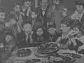 Eugénie Duchoiselle inmitten einer Vielzahl von Kindern während eines Neujahrskuchen-Essens, grobkörniges Schwarzweißbild