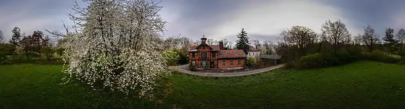Das Panoramafoto zeigt das Gebäudeensemble des Garnisonsschützenhauses und den prachtvoll blühenden, weit ausladenden Kirschbaum in seiner unmittelbaren Nähe.