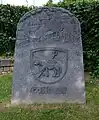 Historienstein mit dem Wappen der Abtei Stablo und der Jahreszahl 857, Basaltlava, 2016, von Karl-Rudolf Müller, neben dem alten Kirchenschiff