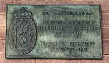 Messingschild mit Wappen und Inschrift: ZUR ERINNERUNG AN DAS KÖNIGLICH PREUSSISCHE KADETTENHAUS KARLSRUHE 1892–1919 UND SEINEN GEFALLENEN ZUM GEDÄCHTNIS