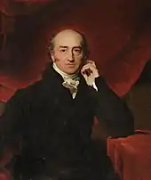 Gemälde George Cannings, der den Betrachter des Bilds frontal ansieht. Er trägt einen dunklen Anzug, sein linker Ellenbogen ruht auf einem gepolsterten Beitisch. Sein Blick ist ernst, sein Haaransatz weicht bereits deutlich zurück.