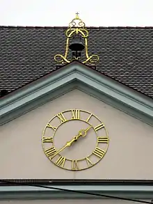 	Giebel der früheren Karlskaserne am Freiburger Europaplatz mit Uhr und Glockenaufhängung des abgebrochenen zweiten Christophstores in Form eines doppelten L. Die Bourbonenlilie auf der Krone wurde durch ein Kreuz ersetzt, so widmete man das ursprüngliche Initial des französischen Königs Ludwig XIV. dem badischen Großherzog Ludwig II.