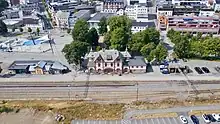 Drohnenfoto von einem Bahnhofsgebäude, dahinter städtische Bebauung